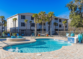 Resort-style pool with sundeck and chaise lounges and hammock.